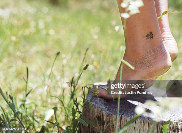 woman balancing on tree stump, kanji character tattooed on ankle - kanji stock pictures, royalty-free photos & images