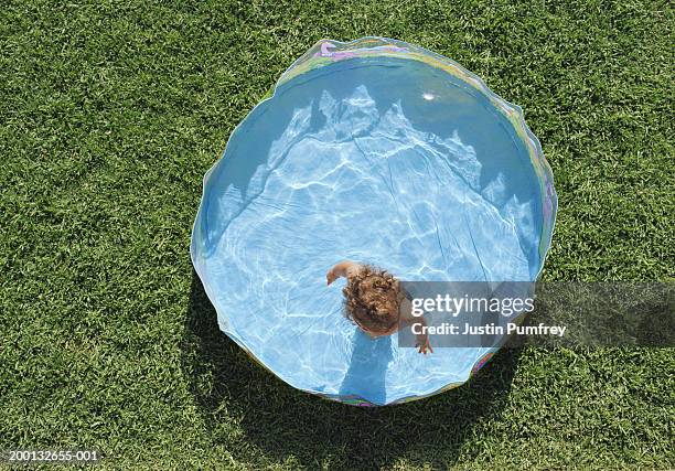 baby girl (21-24 months) in paddling pool, overhead view - planschbecken stock-fotos und bilder