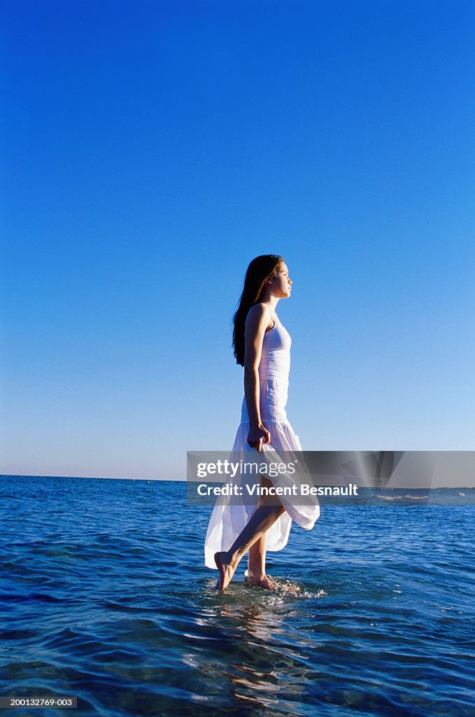Teenage girl (15-17) walking on surface of sea, side view