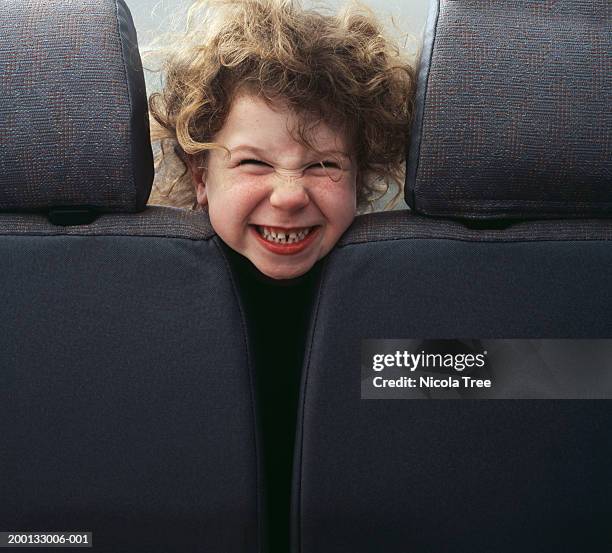 girl (4-6) looking through two car seats, smiling, portrait - face irritation stock pictures, royalty-free photos & images