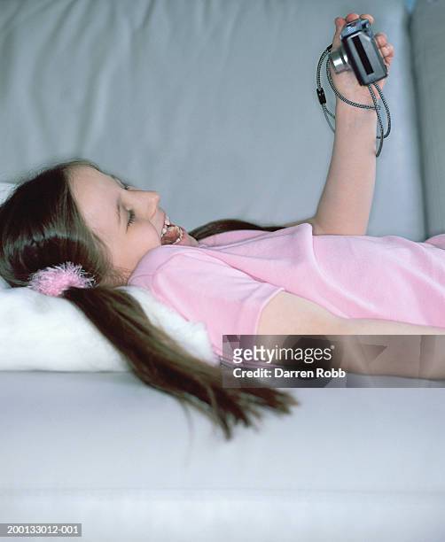girl (7-9) lying on back taking photograph of herself laughing - lying on back girl on the sofa stock-fotos und bilder