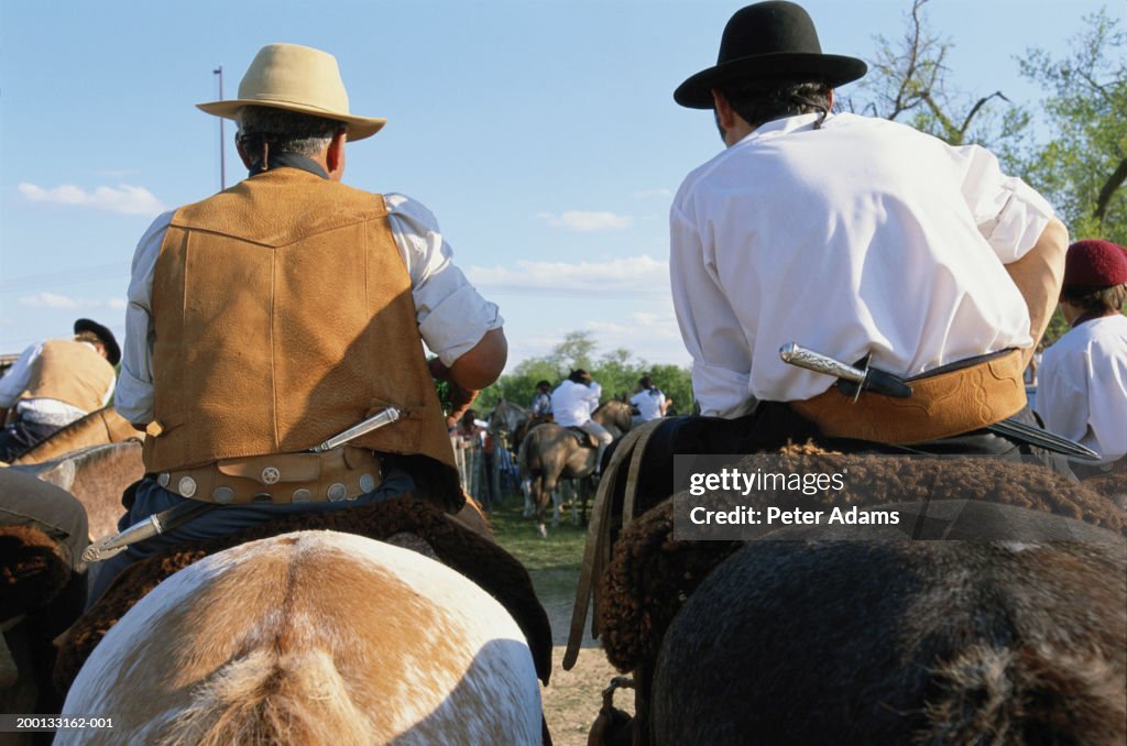 Gauchos on horseback, rear view