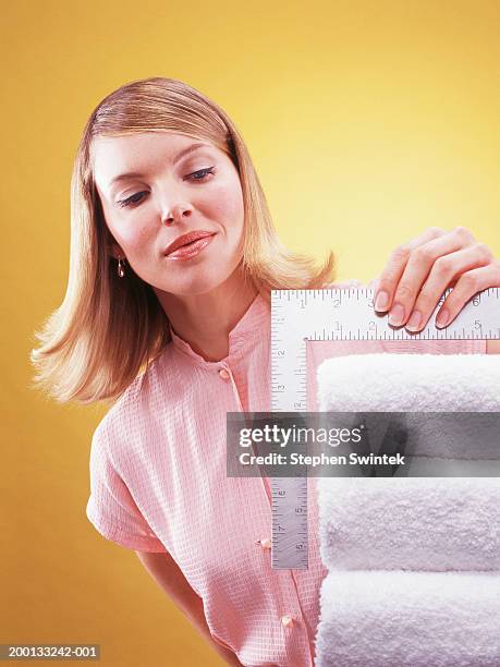 woman measuring stack of folded towels - obsessive stockfoto's en -beelden