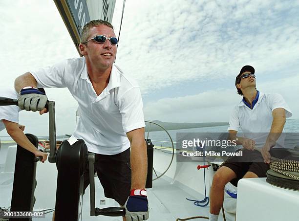 man tacking sailing ocean going racing yacht, crew in background - sailing tacking stockfoto's en -beelden