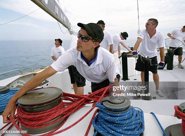 man wrapping lines around crank, sailing ocean going racing yacht - boat crew stock pictures, royalty-free photos & images