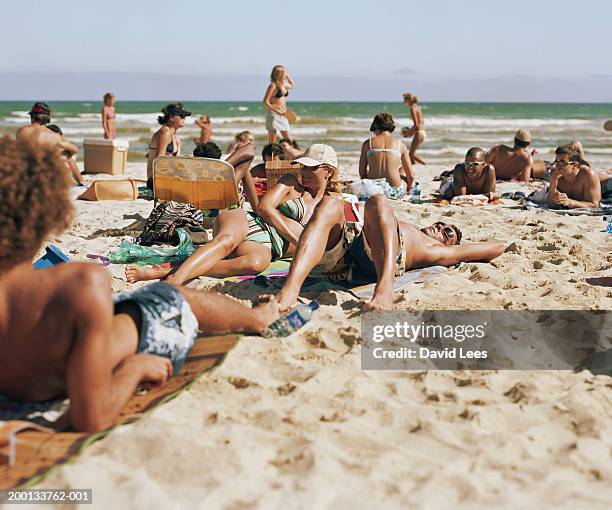 people on beach (focus on couple in centre of crowd) - crowded beach stock pictures, royalty-free photos & images