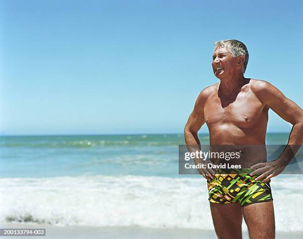 mature man on beach, hands on hips - brunbränd bildbanksfoton och bilder