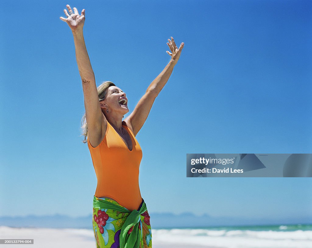 Mature woman on beach, arms raised