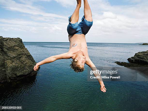 young man doing somersault into water below - northland new zealand stock pictures, royalty-free photos & images