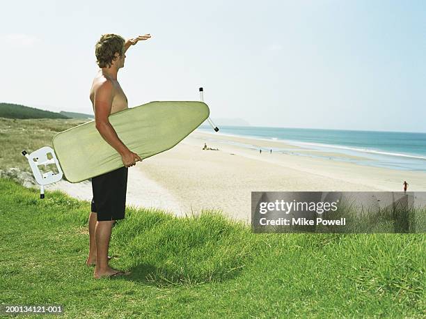 young man holding ironing board on beach - unter dem arm stock-fotos und bilder