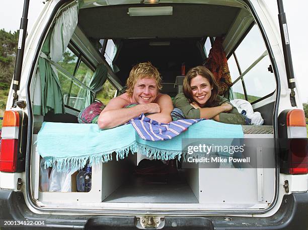 young couple lying inside camper van, portrait - woman smiling facing down stock pictures, royalty-free photos & images