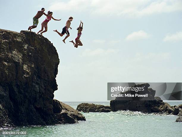 grupo de amigos salto en mar desde rock acantilado - just do it fotografías e imágenes de stock