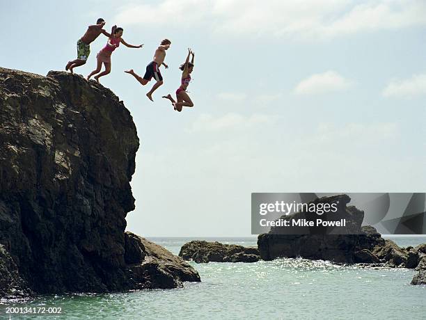 gruppo di amici di saltare nell'oceano dalla scogliera di roccia - strapiombo foto e immagini stock