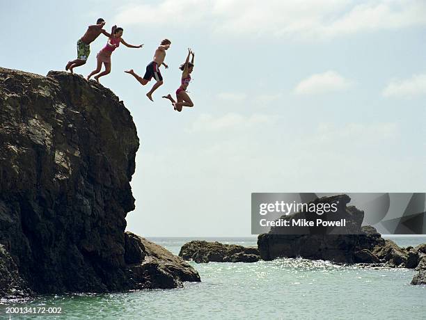 group of friends jumping into ocean from rock cliff - bluff nz stock pictures, royalty-free photos & images