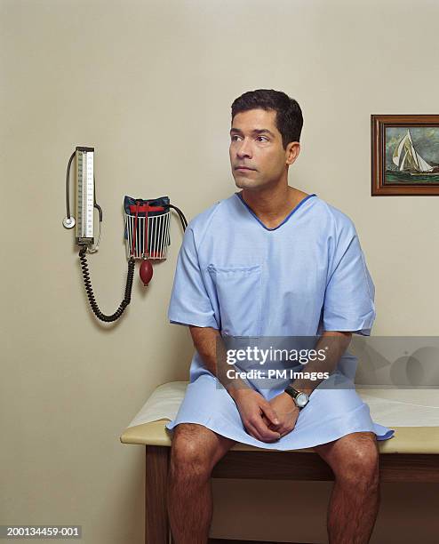 male patient sitting on examining room table - examination table stock pictures, royalty-free photos & images