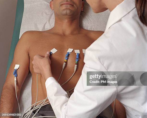 female doctor giving male patient ekg, mid section, elevated view - pulse trace - fotografias e filmes do acervo