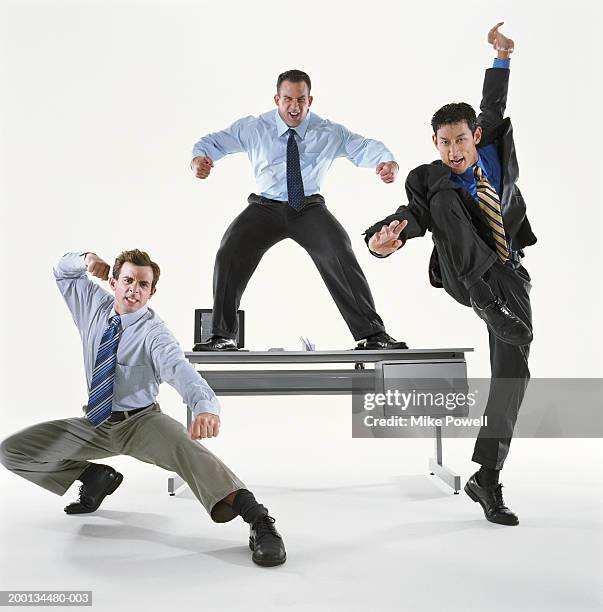 businessmen in different action posses, one standing on desk - action hero foto e immagini stock