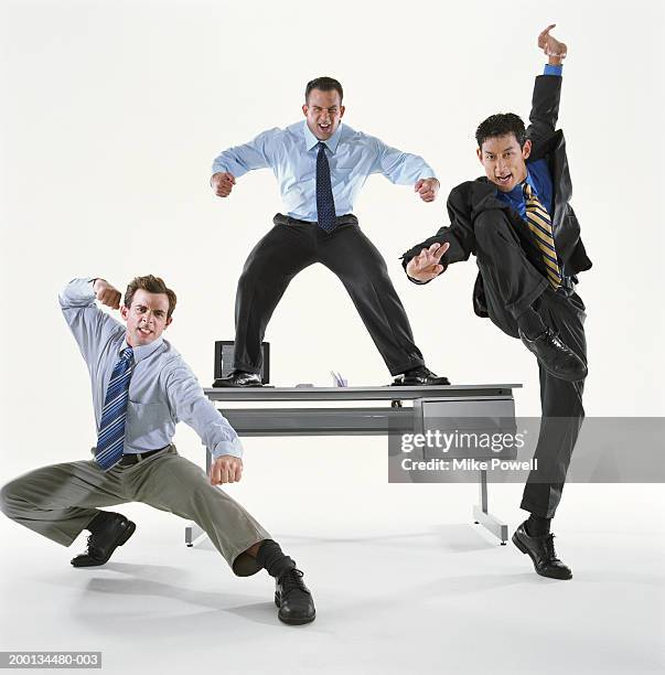 businessmen in different action posses, one standing on desk - action hero ストックフォトと画像