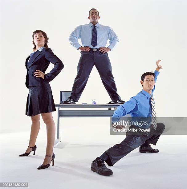 businessmen and woman standing by desk, one man in karate pose - heroes stock-fotos und bilder