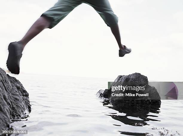 young man jumping between rocks, low section (blurred motion) - tomorrow stock-fotos und bilder