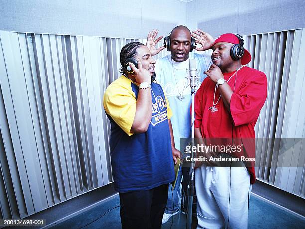 three men in recording studio singing in to microphone - rap group stockfoto's en -beelden