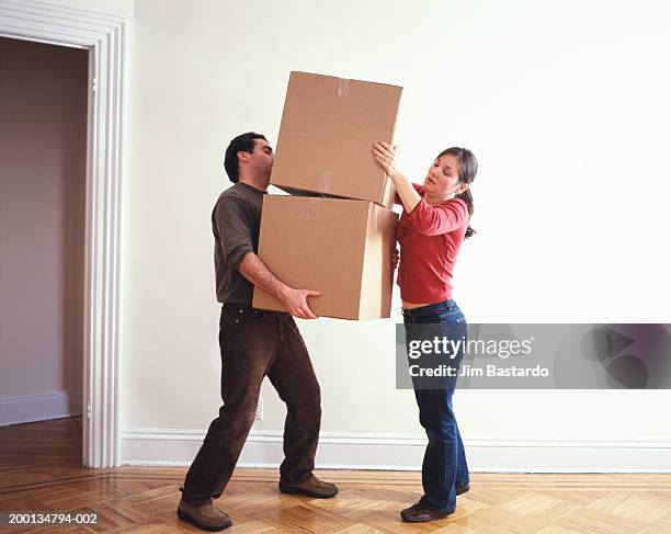 woman handing box to man in bare room - side view carrying stock pictures, royalty-free photos & images
