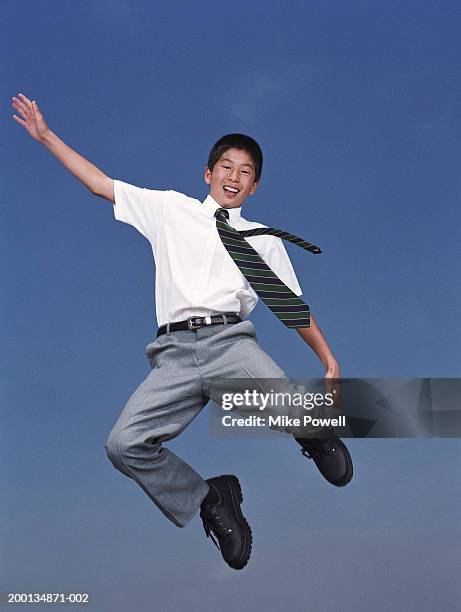 boy (12-14) wearing school uniform, jumping in air, portrait - school tie stock-fotos und bilder