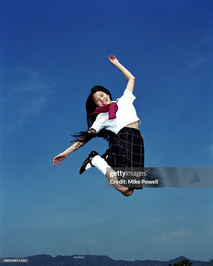Femme (12 à 14) en Uniforme scolaire, sauter en l'air, portrait
