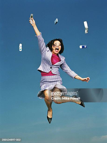 businesswoman jumping with mobile phones in air, low angle - women open mouth stock pictures, royalty-free photos & images