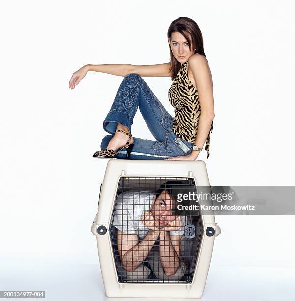 young woman on top of dog cage containing man, portrait - portrait woman looking at camera brave stock-fotos und bilder