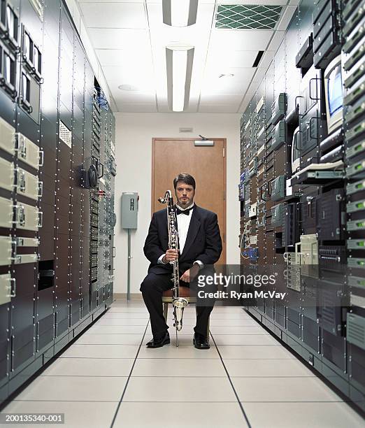man holding bass clarinet, sitting in server room, portrait - smoking activity stock-fotos und bilder