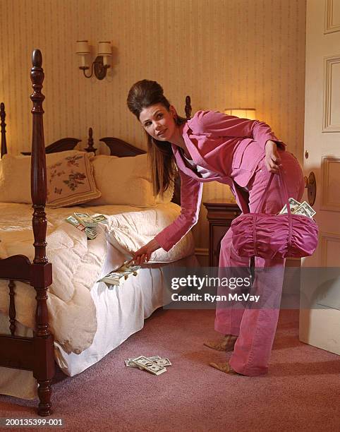 young woman hiding money under mattress - hiding money stock pictures, royalty-free photos & images