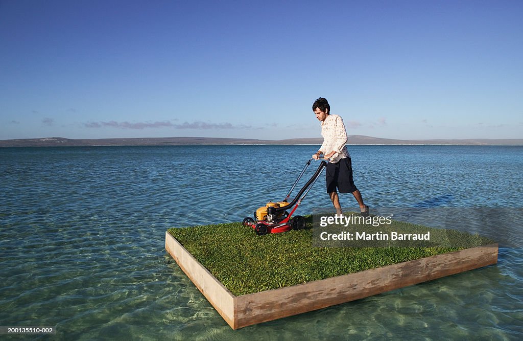 Young man mowing grass on raft at sea