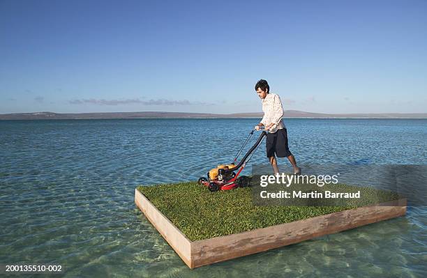 young man mowing grass on raft at sea - ohne zusammenhang stock-fotos und bilder