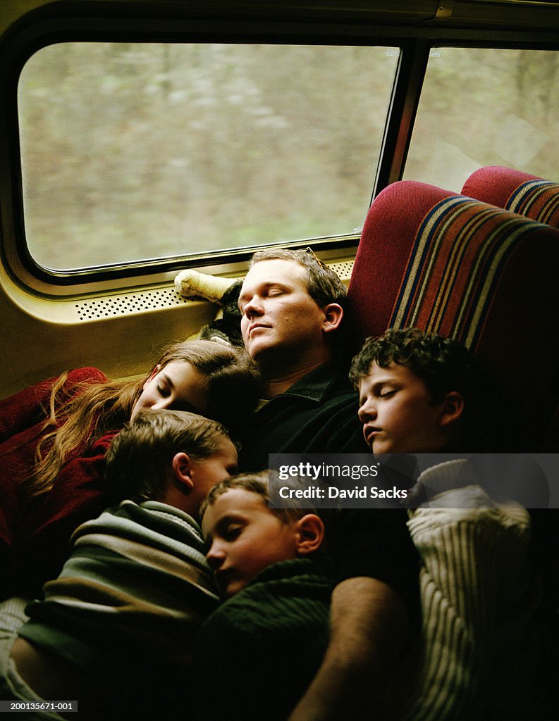 Father and children (4-10) sleeping on train