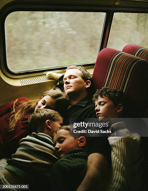 father and children (4-10) sleeping on train - train photos et images de collection