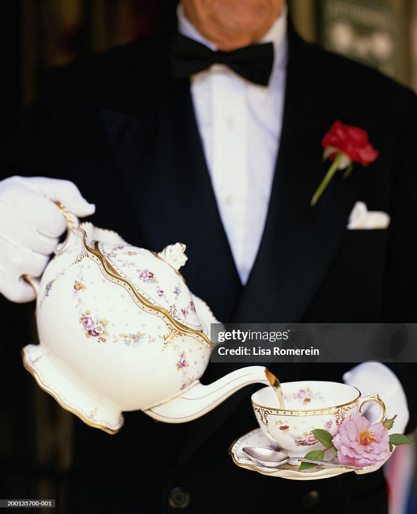 Waiter  wearing white gloves pouring tea into cup (mid section)