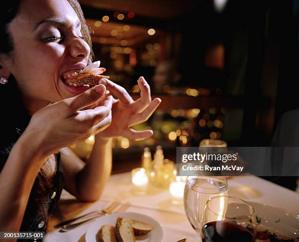 young woman eating appetizer, sitting at restaurant - häppchen stock-fotos und bilder