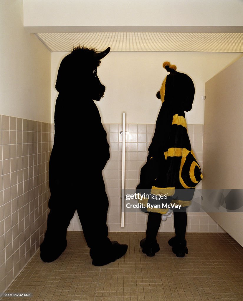Bee and bull having conversation while at  urinal, rear view