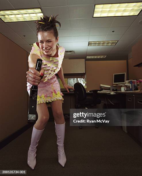 woman in dress made of office supplies having fun with stapler - staples office stockfoto's en -beelden