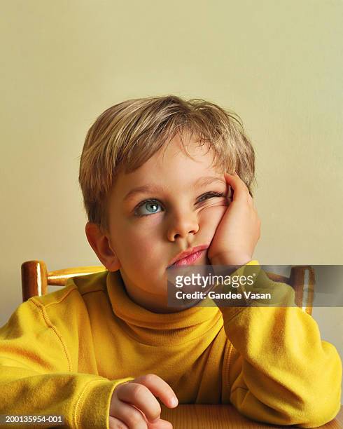boy (4-6) looking up resting cheek in hand    (digital enhancement) - boredom stock pictures, royalty-free photos & images