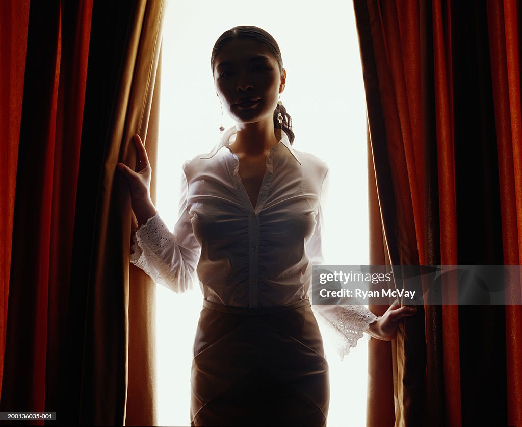 Giovane Donna Guardando Attraverso Tende Rosse Controluce Foto stock -  Getty Images