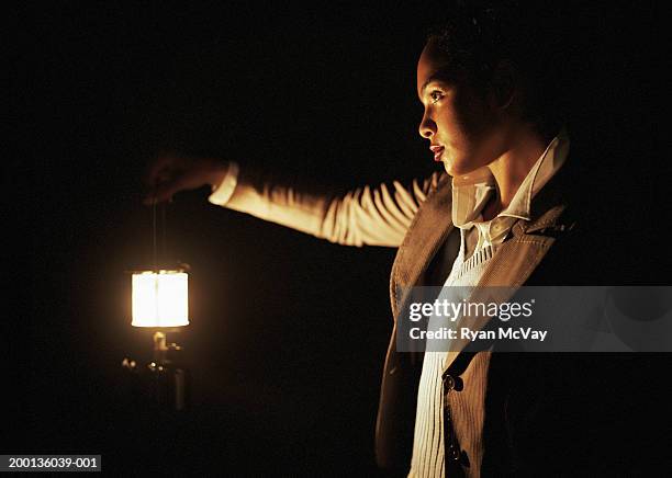 young woman walking through the dark with lantern, side view - lampions stockfoto's en -beelden