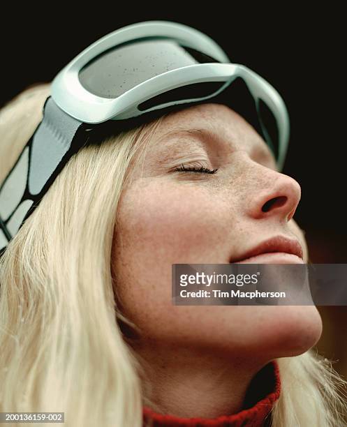 young woman wearing ski goggles, eyes-closed, close-up - wintersport stock-fotos und bilder