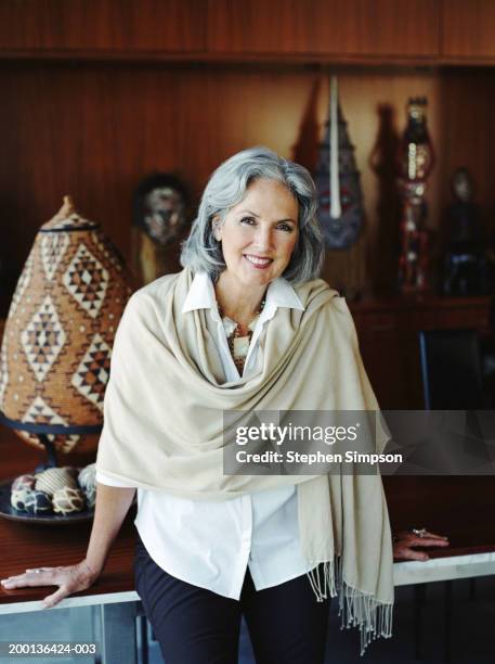 mature woman sitting on table, art pieces in background, portrait - brown eyes stock pictures, royalty-free photos & images