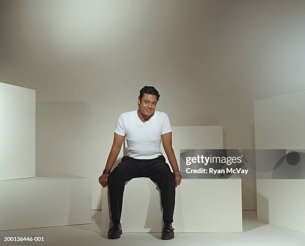 young man sitting on bench, portrait - white/black shirt stock-fotos und bilder