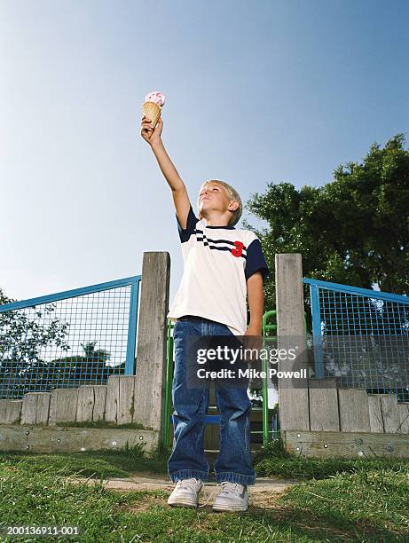 boy (5-7) holding ice cream cone in air like torch - boys sport pants stock pictures, royalty-free photos & images