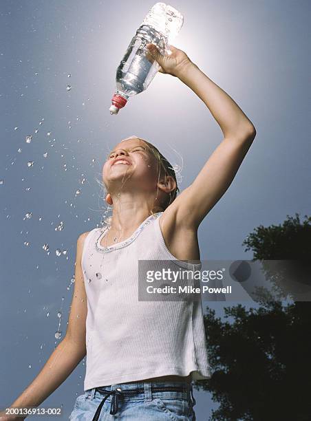 girl (8-10) squirting bottled water on head like athlete - girl wet casual clothing stock pictures, royalty-free photos & images