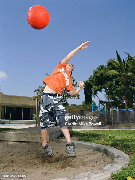 boy (7-9) on playground, pretending to shot putt with rubber ball - kugelstoßen stock-fotos und bilder