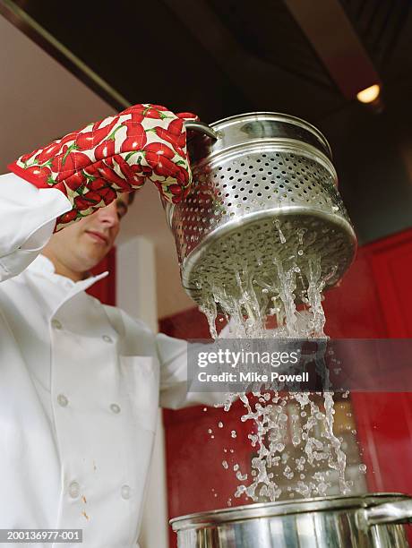 chef  lifting strainer from cooking pot - scolapasta foto e immagini stock